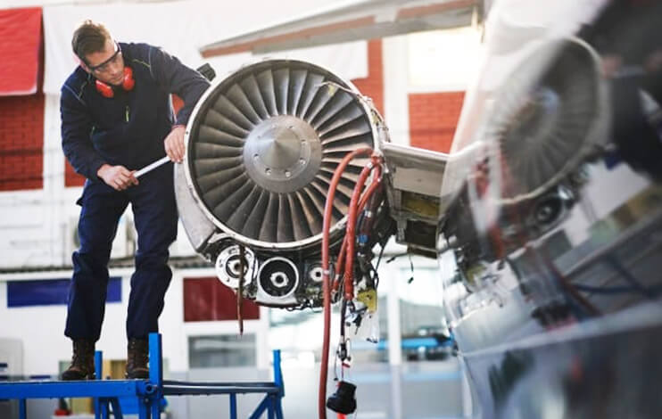 Aircraft mechanic looking at a Boeing 757 engine.