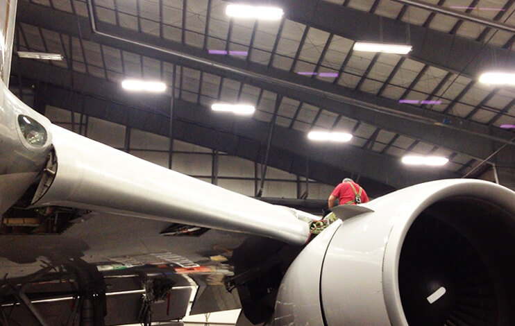 Aircraft mechanic working on top of a Boeing 757 engine pylon.